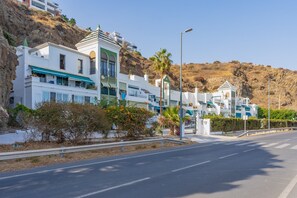 A coastal road with white buildings, a clear sky, and a hilly backdrop. - GuestReady - Beachfront in Torrox (Torrox Costa)