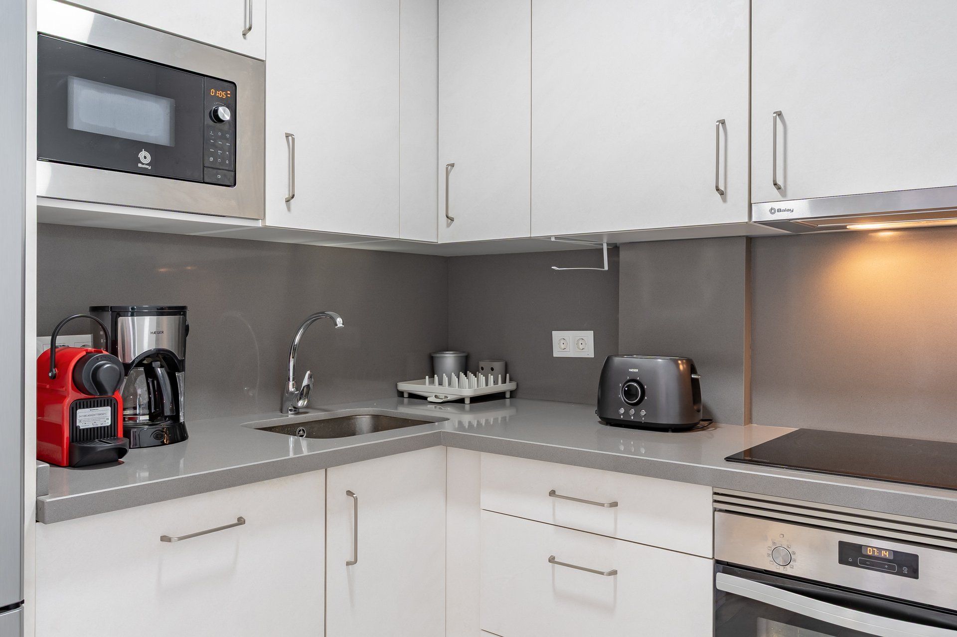 Een moderne keuken met een magnetron, koffiezetapparaat, waterkoker, broodrooster en oven.