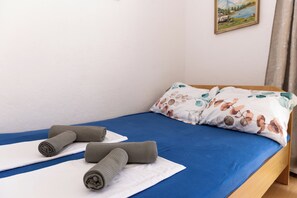 A neatly made bed with blue sheets and a floral pillow, two rolled-up towels on a white mat, and a painting on the wall. - A1 - apartment near beach with two balconies and sea view (Kaštel Gomilica)