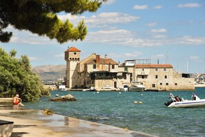 A coastal town with stone buildings, a tower, and boats in the water. - A1 - apartment near beach with two balconies and sea view (Kaštel Gomilica)