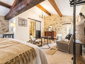 A bedroom with a bed, a chair, a table, and a sofa. - Spacious countryside cottage with garden - 10 guests (Port-Saint-Père)