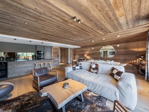 A modern interior with a wooden ceiling, a dining area with a round table, and a sofa with patterned cushions. - Apartment in Mont d'Arbois - 6 guests (Megève)