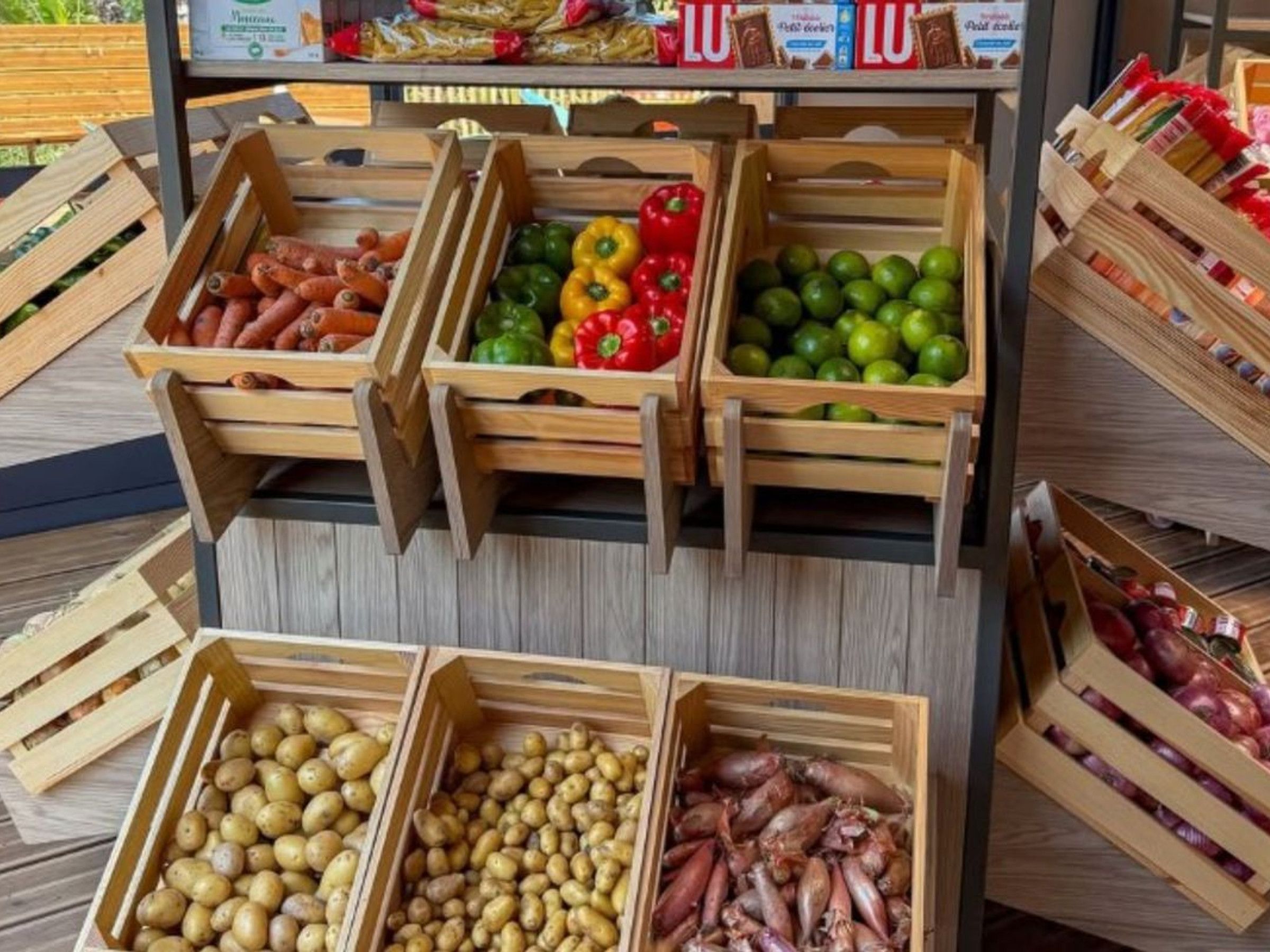 Wooden crates of various vegetables and meats on display.