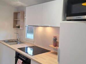 A modern kitchen with a Bosch microwave, a sink, and a window. - Air-conditioned mobile home - 6 guests (Sainte-Marie-la-Mer)