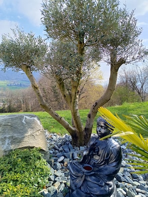 A statue of a seated figure with a tree behind it.