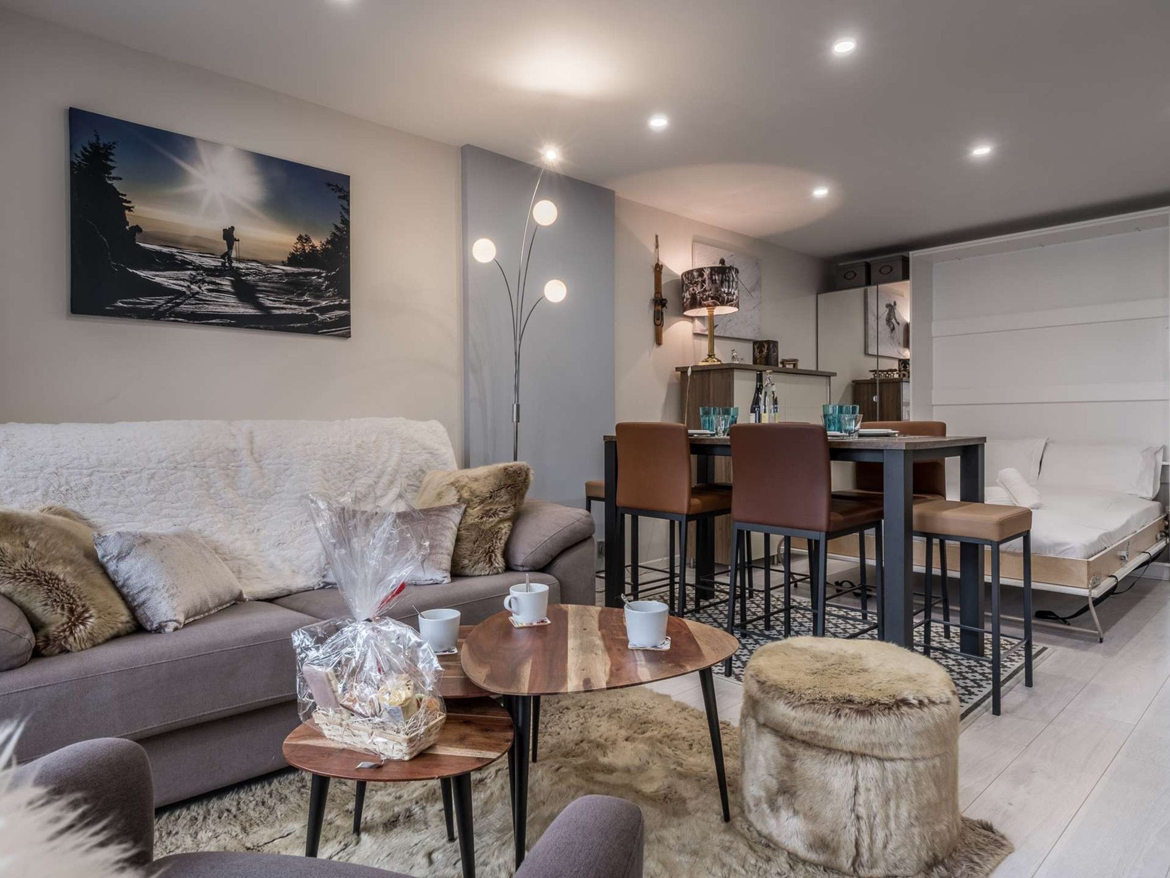 A modern living room with a sofa, coffee table, ottoman, dining table, chairs, and a painting on the wall.