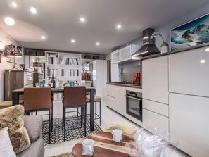 A modern kitchen with white cabinets, a dining area with a table and chairs, and a sofa. - Ski-in/ski-out apartment - 4 guests (Courchevel 1650)