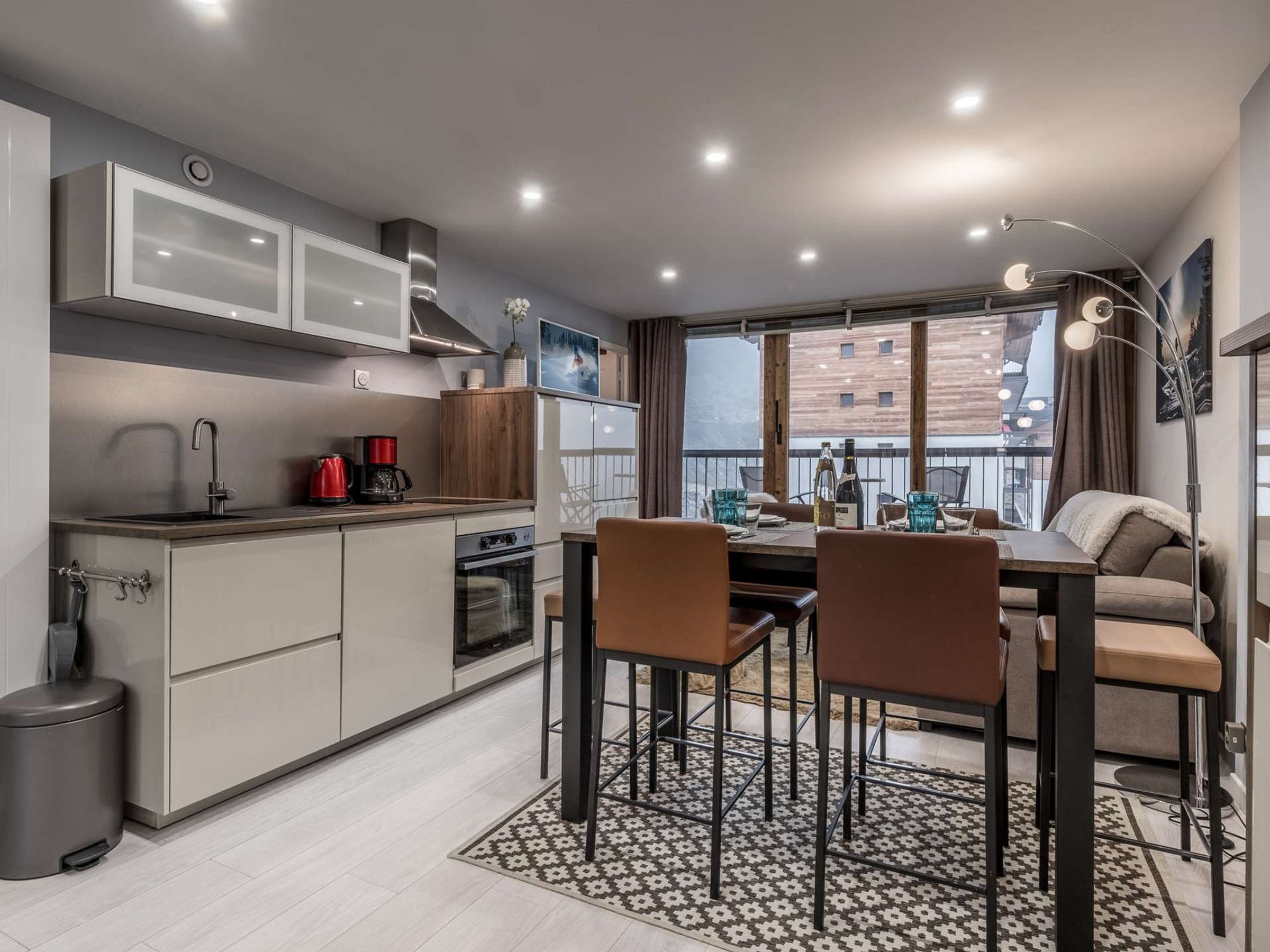 A modern kitchen with a dining area, a view of the city, and a balcony.