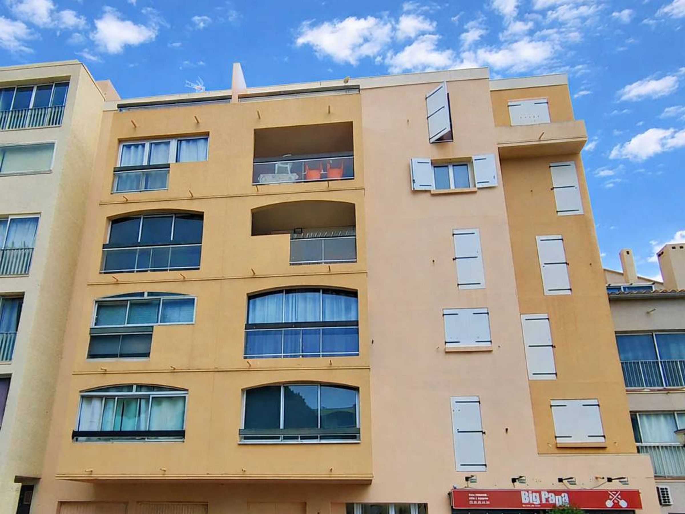 A multi-story building with balconies and large windows, featuring a sign for 'Big Pan' restaurant.