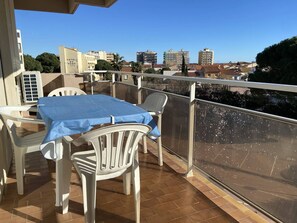 Un balcón con una mesa y sillas, vista del paisaje urbano, y un edificio identificado como HOTEL DU PORT.