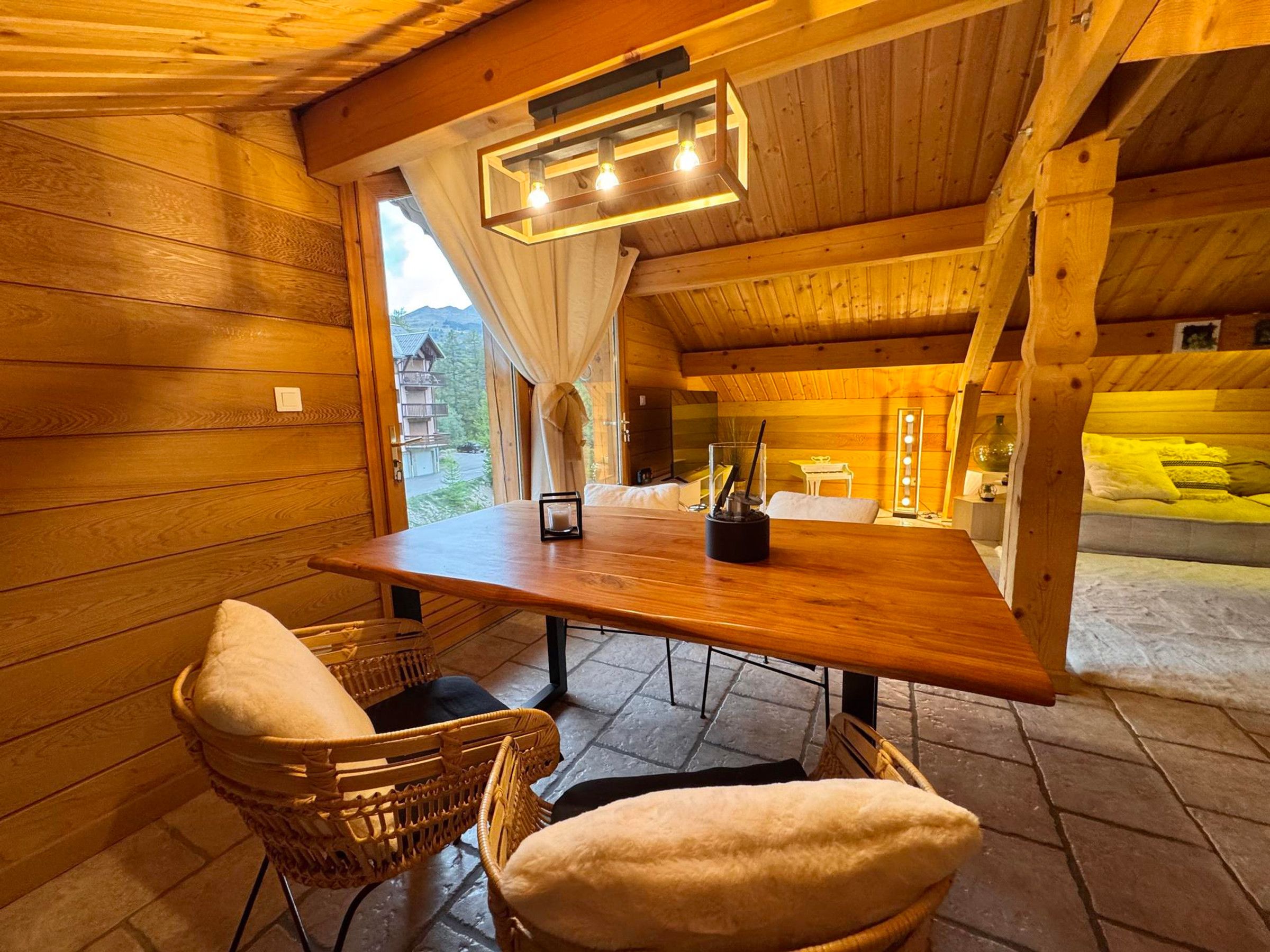 A wooden interior with a table, chairs, and a view of the outside.