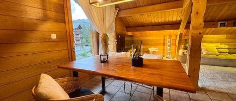 A wooden interior with a table, chairs, and a view of the outside.