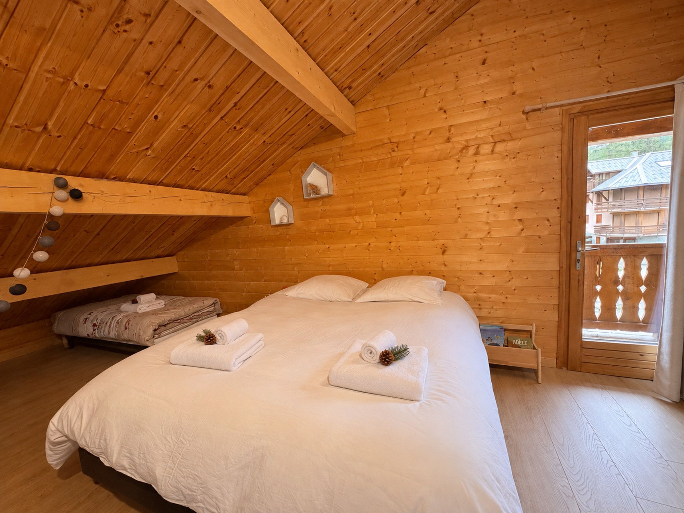 Ein Schlafzimmer einer Holzhütte mit einem Bett, Kissen, einem Nachttisch und einem Fenster.