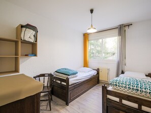 A bedroom with two beds, a wooden chair, a desk, and a window with curtains. - Pleasant apartment, mountain view - 6 guests (Villard-de-Lans)