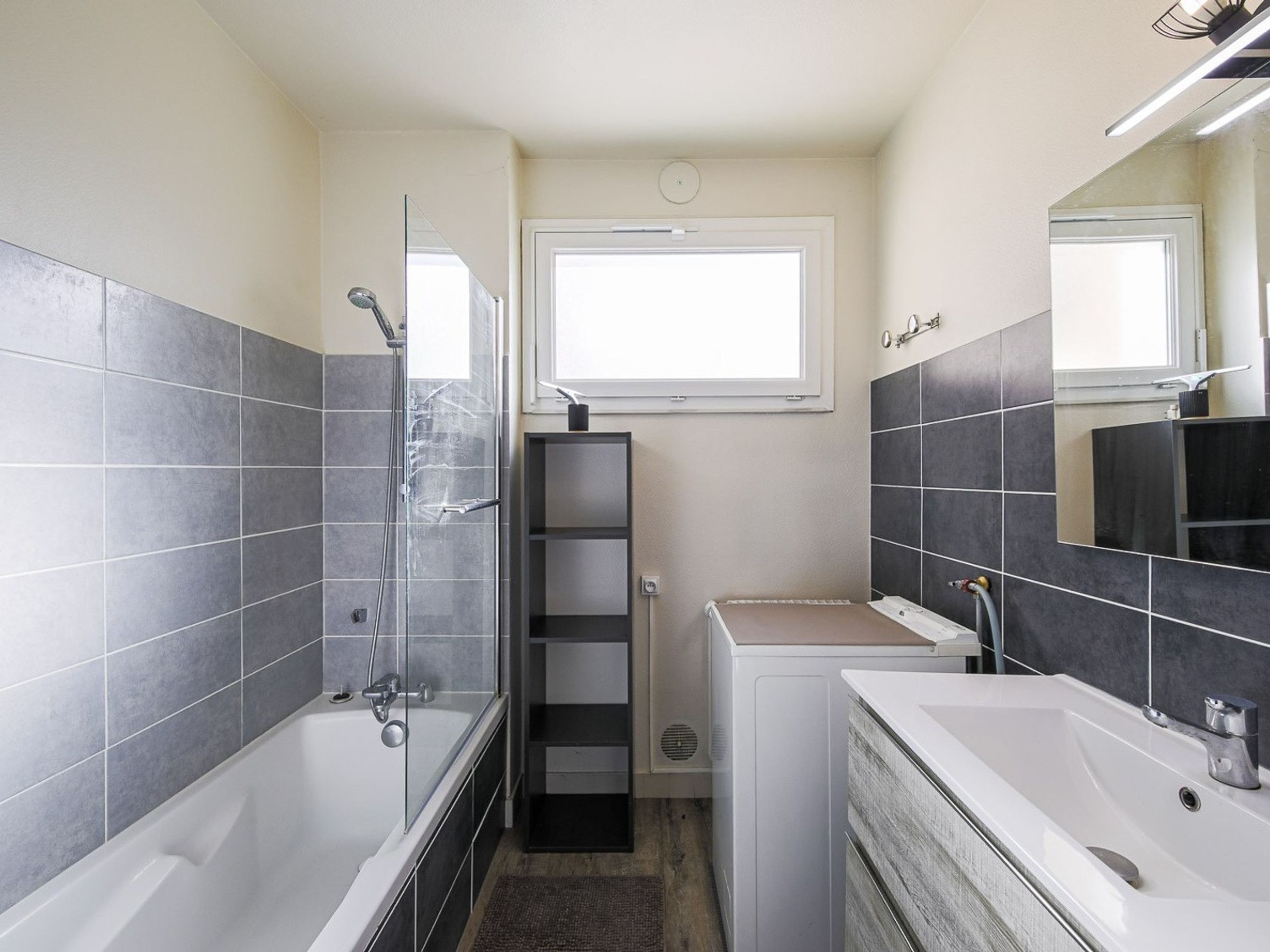 Un baño con bañera, ducha, lavamanos y espejo.