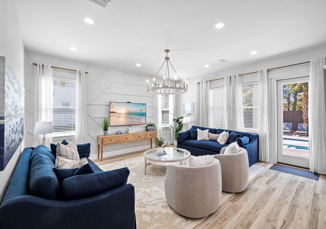 A modern living room with a sofa set, ottomans, a coffee table, and a chandelier.