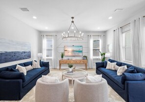 A modern living room with two sofas, a coffee table, and a TV. - Blue Lagoon: Private beach access, FREE Golf cart, Heated pool, Arcade Room (Miramar Beach)