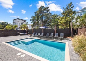 A rectangular swimming pool with a tiled edge, surrounded by lounge chairs and a wooden fence. - Blue Lagoon: Private beach access, FREE Golf cart, Heated pool, Arcade Room (Miramar Beach)