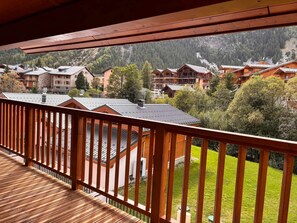 Ein Holzbalkon mit Blick auf ein Wohngebiet und einen Berg im Hintergrund.