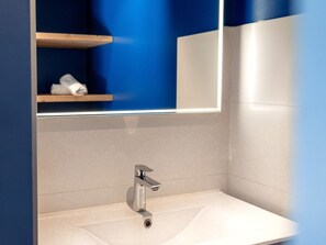 Une salle de bain moderne avec un lavabo blanc, un robinet chromé et un miroir au-dessus.