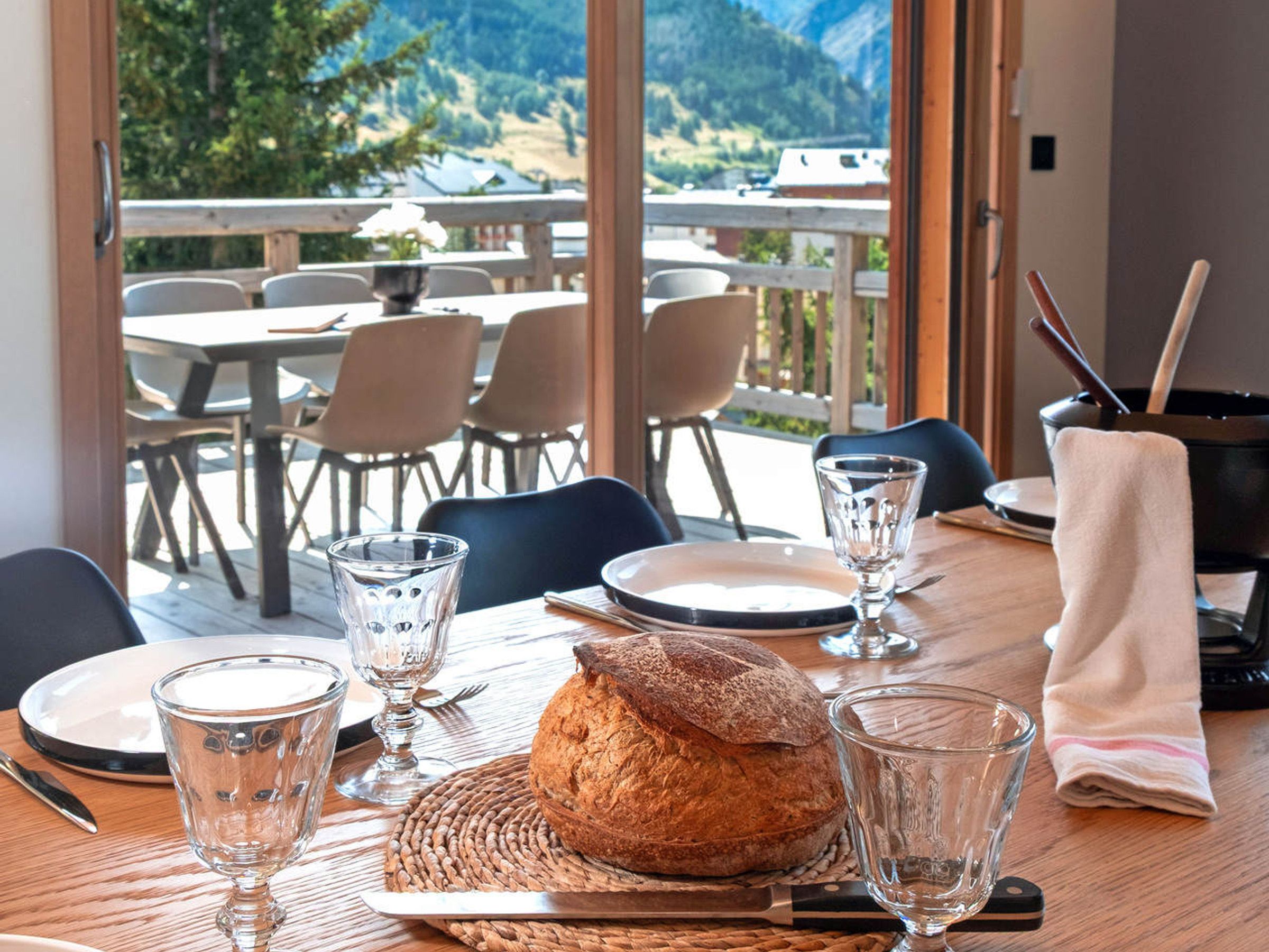 Ein Esstisch gedeckt mit Tellern, Gläsern, Brot und Besteck.