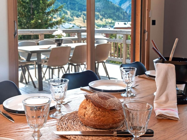 Une table à manger dressée avec des assiettes, des verres, une miche de pain et des couverts.