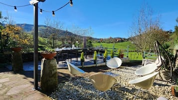 Eine Außenpatio mit Steinböden, einer Pergola, Lichterketten und Gartenmöbeln.
