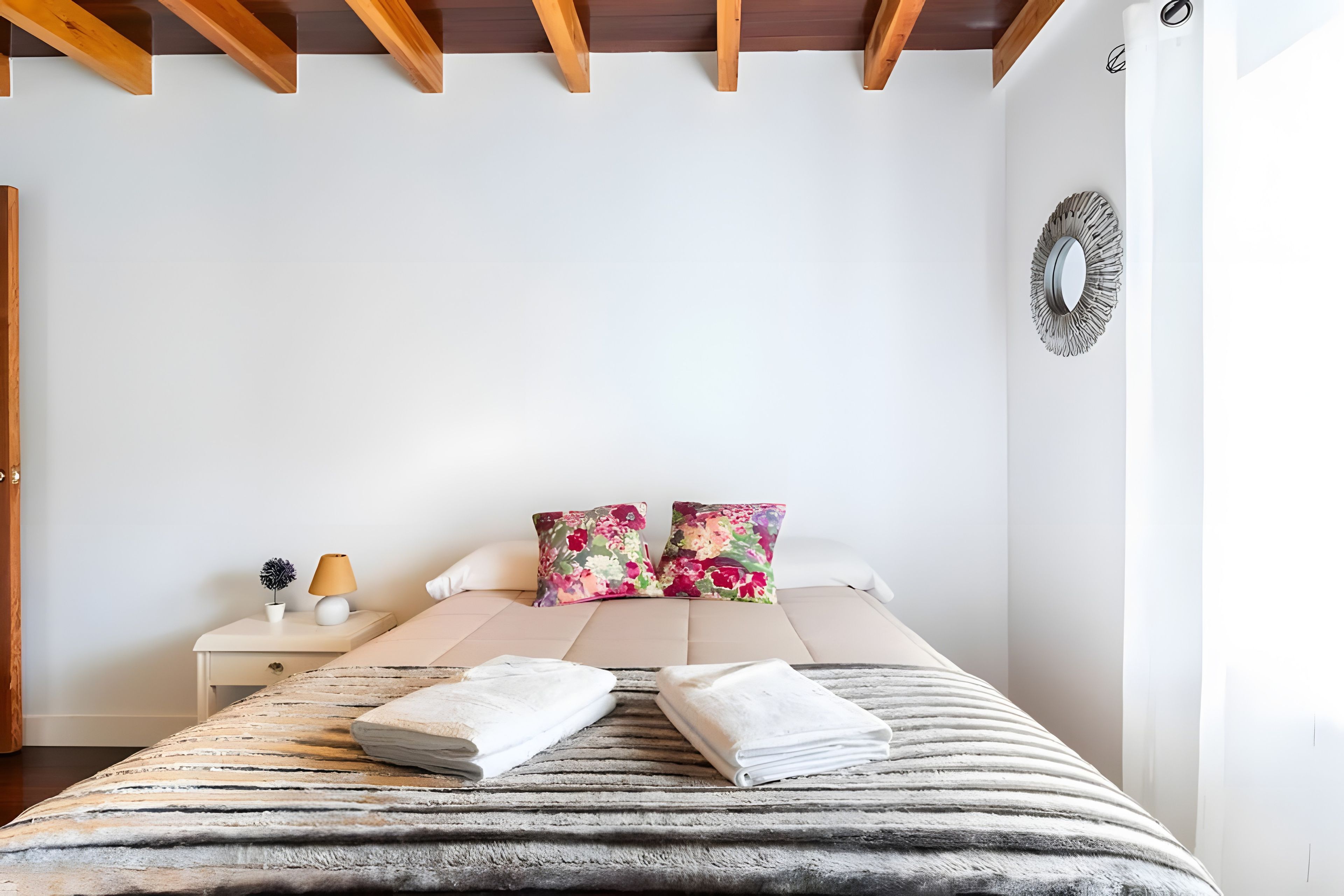 Ein Schlafzimmer mit Bett, Kissen, Nachttisch, Lampe und Wandbild.