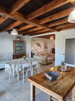A dining area with a table set for four, a wooden bench, and a sofa in the background. - La Esmeralda Country House (Hornedo)