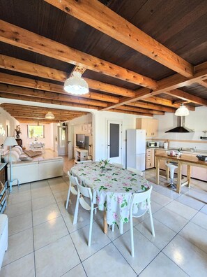 A spacious living area with a dining table, sofas, and a kitchen in the background. - La Esmeralda Country House (Hornedo)