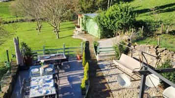 Eine Terrasse im Freien mit Esstisch, umgeben von Topfpflanzen und einem gepflasterten Weg.