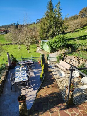 An outdoor patio with a table set for dining, surrounded by potted plants and a stone pathway. - La Esmeralda Country House (Hornedo)