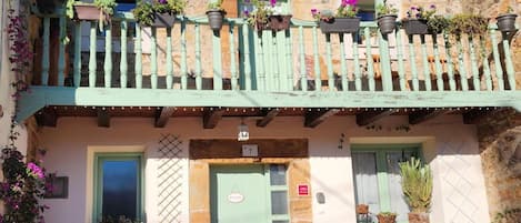 Un edificio de dos pisos con un balcón decorado con macetas de plantas y flores.