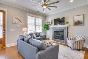 A living room with a grey sofa, striped armchair, fireplace, and a ceiling fan. - Lake Access & Boat Slip: Greenwood Cottage! (Greenwood)
