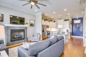 A modern living room with a fireplace, a sofa, a striped armchair, and a television. - Lake Access & Boat Slip: Greenwood Cottage! (Greenwood)