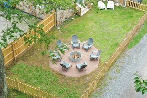 A backyard with a fire pit surrounded by Adirondack chairs, a stone wall, and a wooden fence. - 5 Houses, 19 Bd, 14 BA, 16 Acres, Pool, Events! (Friendsville)