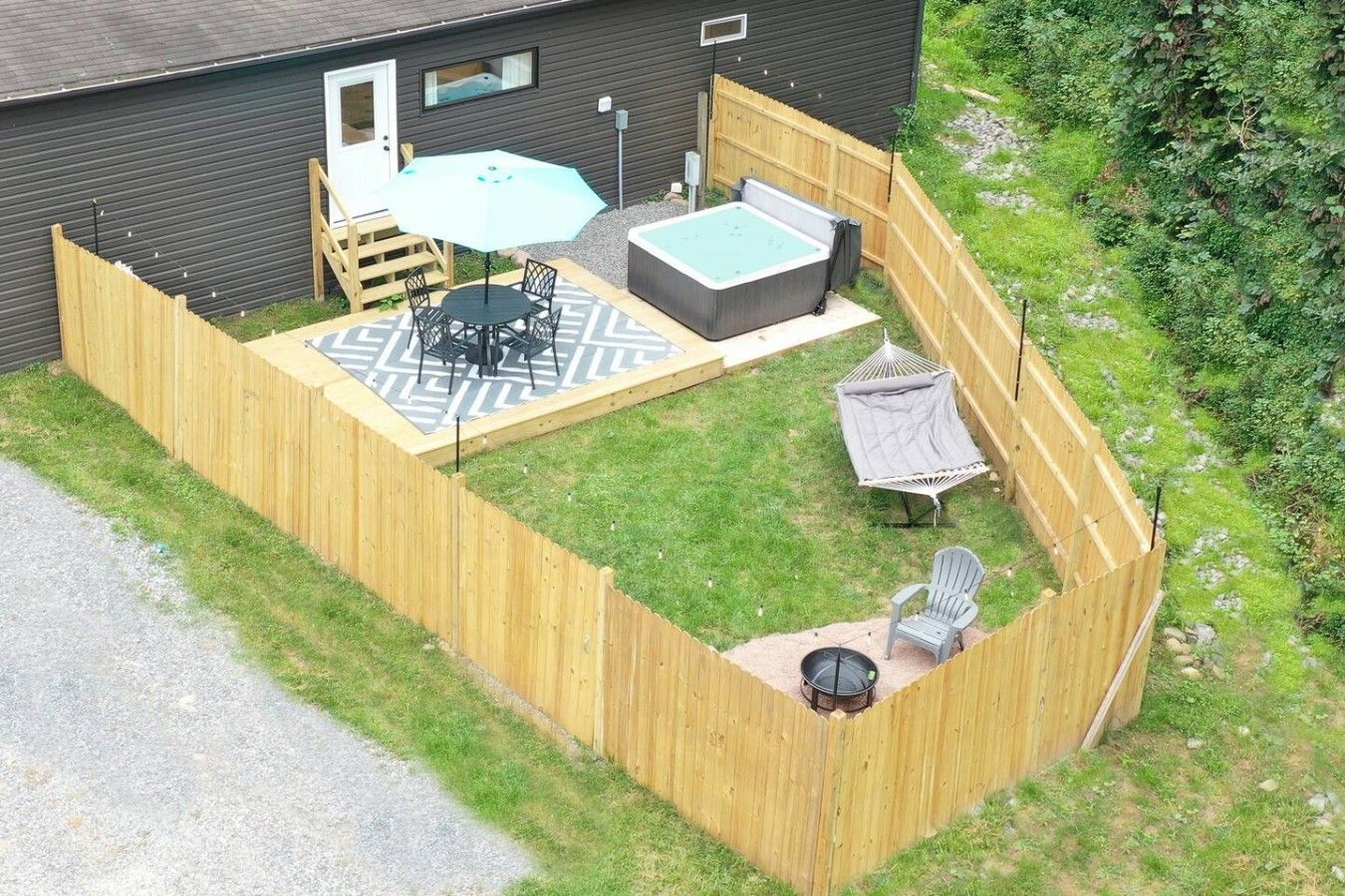 A fenced backyard with a hot tub, patio furniture, and a hammock.