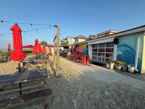 A beachside restaurant with outdoor seating and a mural on the building. - Fishy Fishy UP - 3BR 1BA duplex home @ Yaupon Oak Island Pier & 801 Event Center (Oak Island)