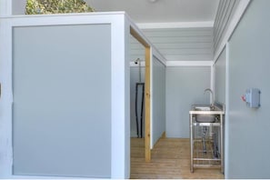 A narrow hallway with a wooden floor, a small metal sink, and a white partition. - Fishy Fishy UP - 3BR 1BA duplex home @ Yaupon Oak Island Pier & 801 Event Center (Oak Island)