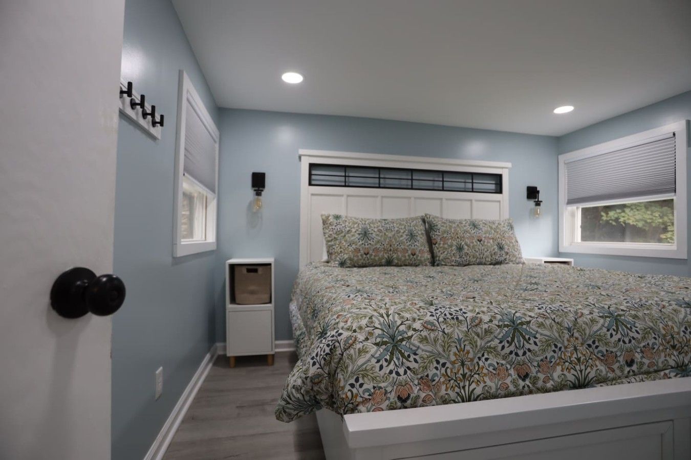 A bedroom with a bed, nightstands, a window, and a door.