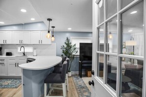 A modern kitchen with white cabinets, a central island, and pendant lighting.