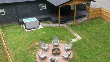 A backyard with a fire pit, outdoor seating, and a covered area with string lights.