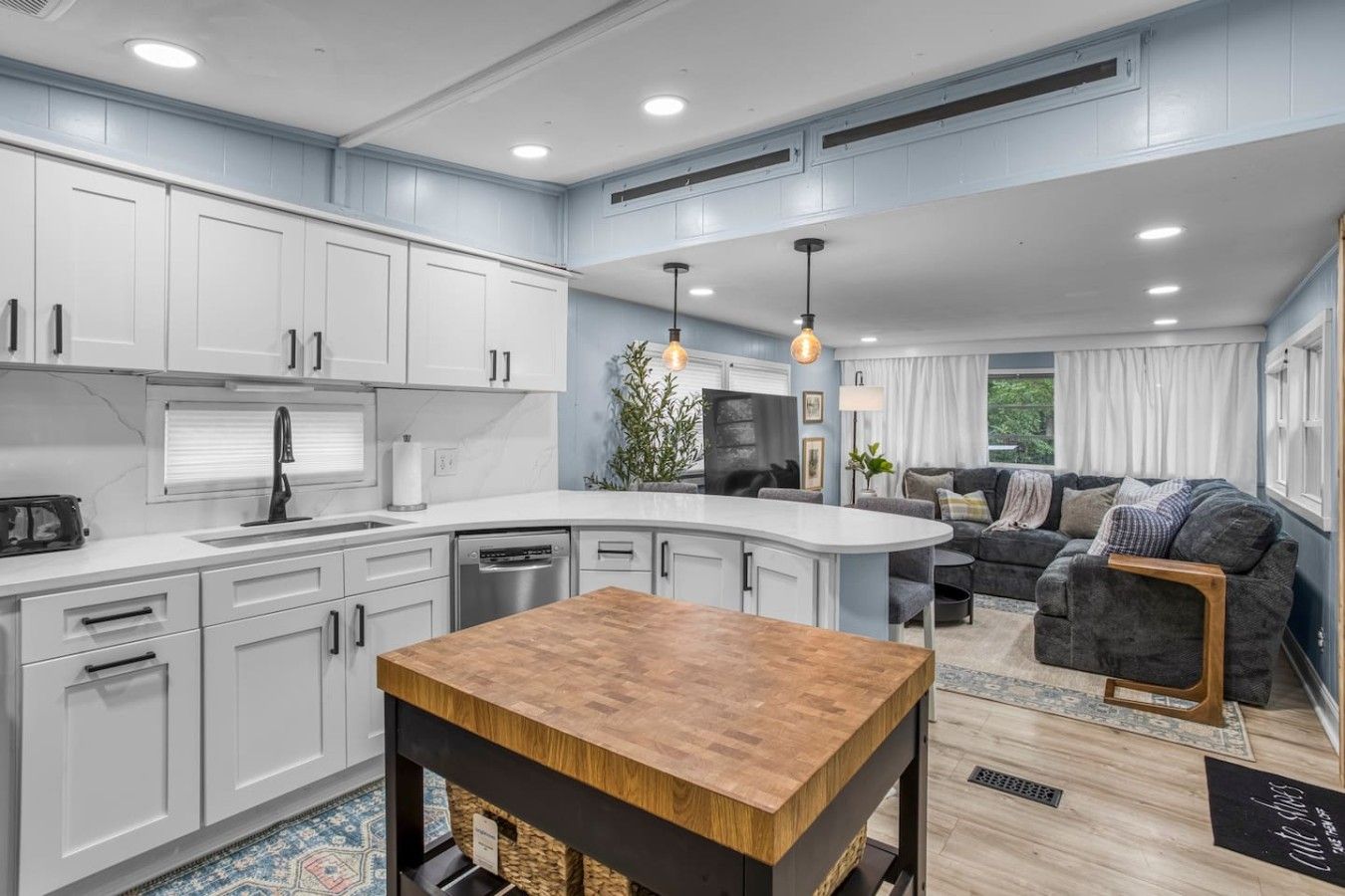 A modern kitchen with white cabinets, a wooden island, and a dining table.
