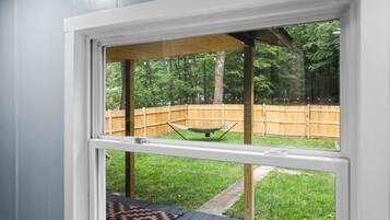 A window with a view of a backyard, including a wooden deck and a hammock.