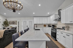 A modern kitchen with white cabinetry, a central island, and a chandelier.