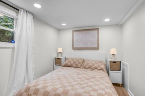 A bedroom with a bed, two bedside tables, a window with curtains, a wall-mounted artwork, and a ceiling light. - New Private 2bd 1 ba, Hot tub, Trails, Waterfront! (Friendsville)