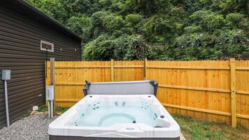 A hot tub in a backyard with a wooden fence and a shed in the background.