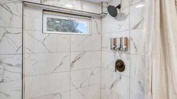 Een badkamer met een douche, een raam en een handdoekhouder.