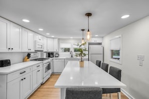 A modern kitchen with white cabinetry, a central island, and pendant lighting. - New Private 2bd 1 ba, Hot tub, Trails, Waterfront! (Friendsville)
