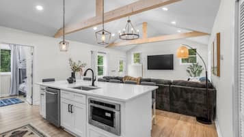 Une cuisine moderne dotée d’un îlot central, d’appareils électroménagers intégrés et de luminaires suspendus.